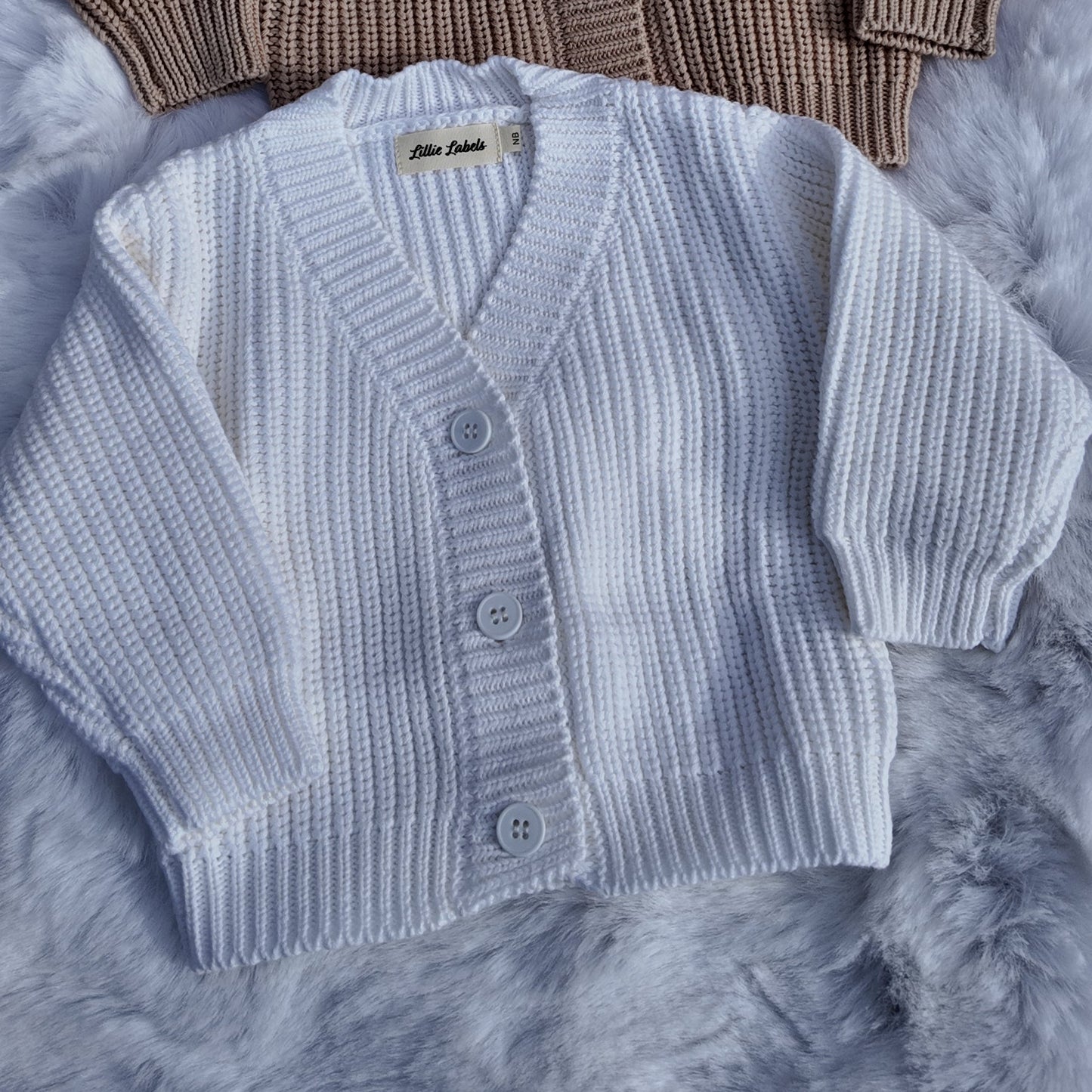 Two knitted cardigans, one brown and one gray, on a textured surface.