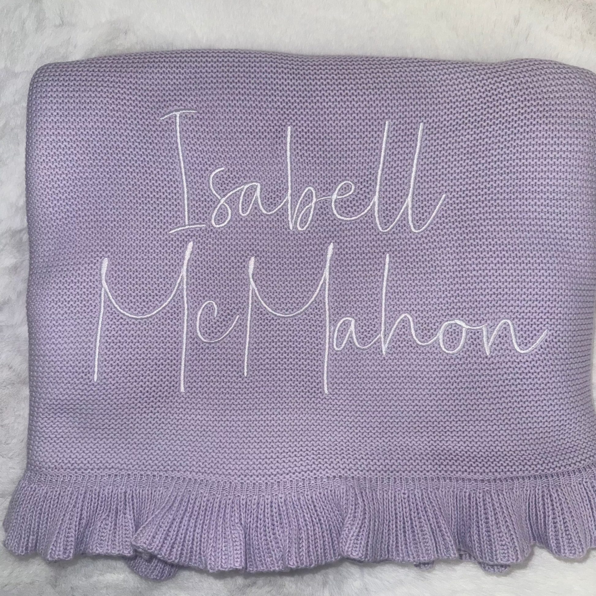 Purple blanket with embroidered name on a soft surface